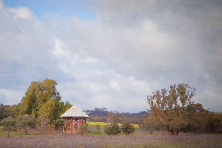 A view to the apiary with a crow on the decorative roof finial, under a drizzly sky in New Norcia.